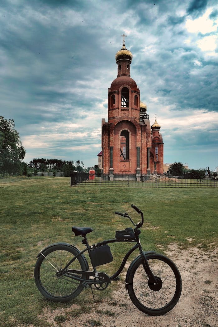 Bicycle parked in front of a picturesque Russian Orthodox church under a dramatic sky.